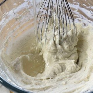 Un primo piano di una frusta in una ciotola di pastella