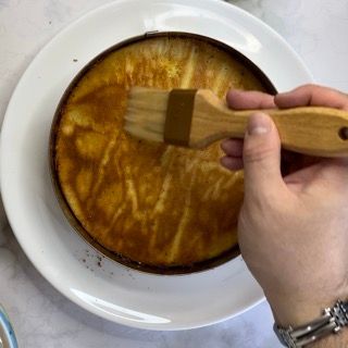 Una persona tiene una spazzola di legno sopra un piatto di cibo