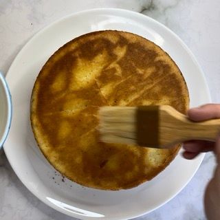 Una persona sta spennellando una torta con una spazzola di legno