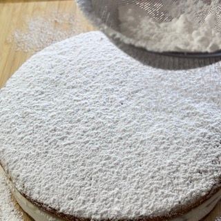Lo zucchero a velo viene versato su una torta con un setaccio.