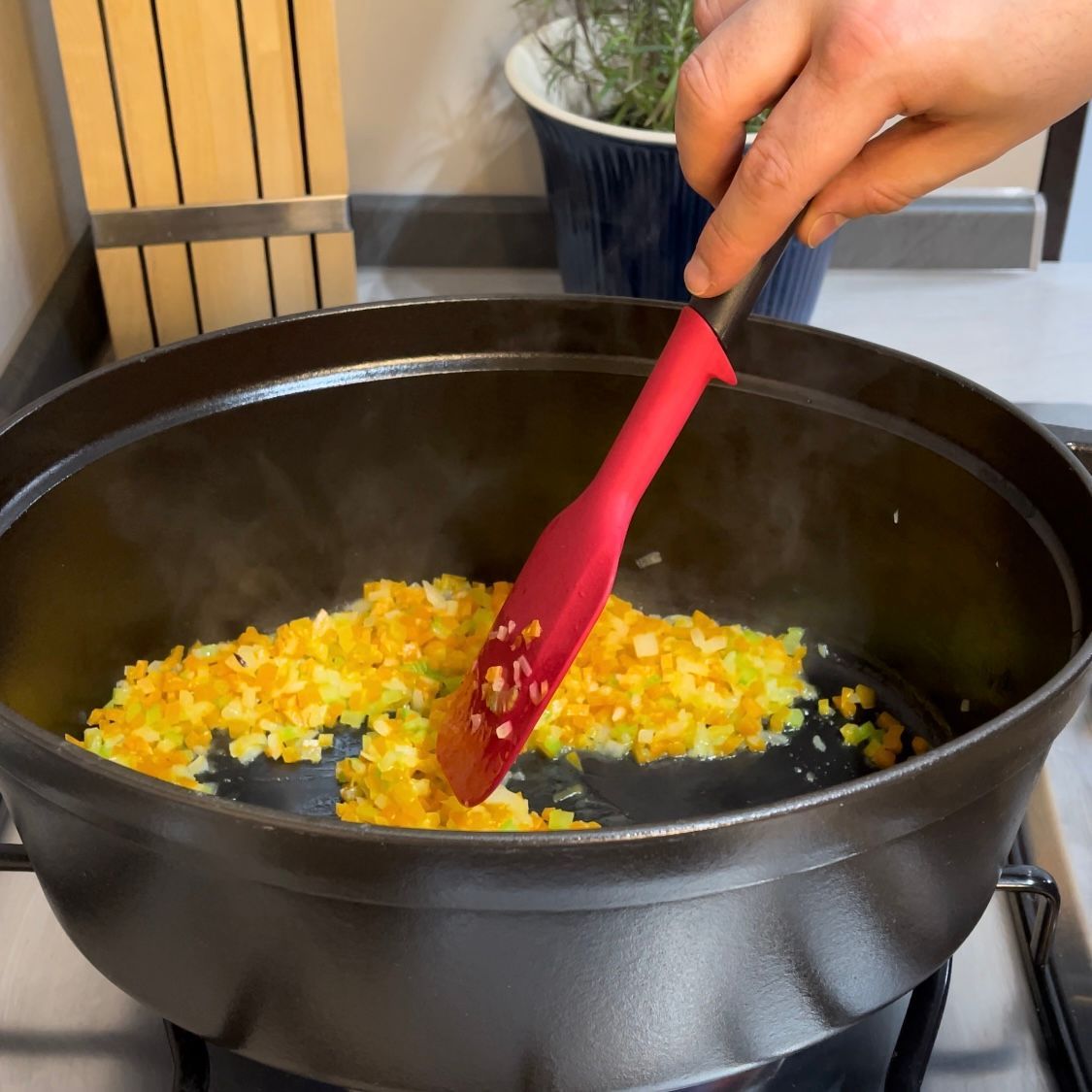 Soffritto di verdure che cuoce dolcemente in pentola con coperchio.