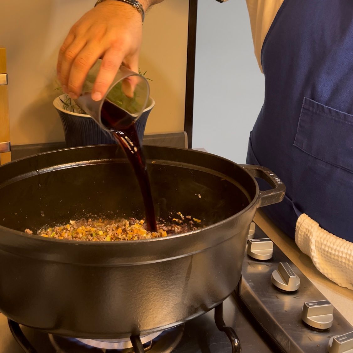 Vino rosso versato nella pentola per sfumare il ragù.
