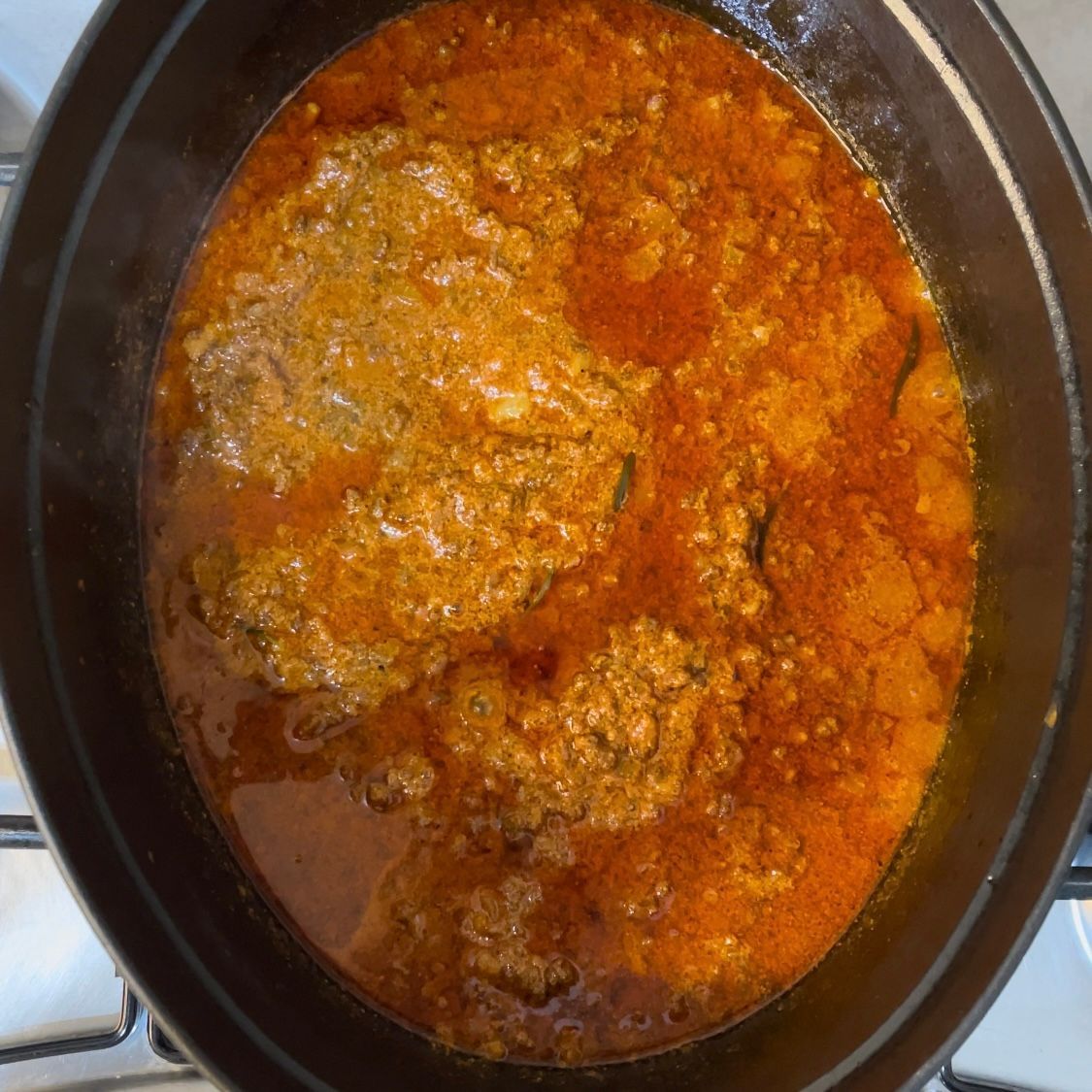 Primo piano del ragù denso e scuro dopo 4 ore di cottura.