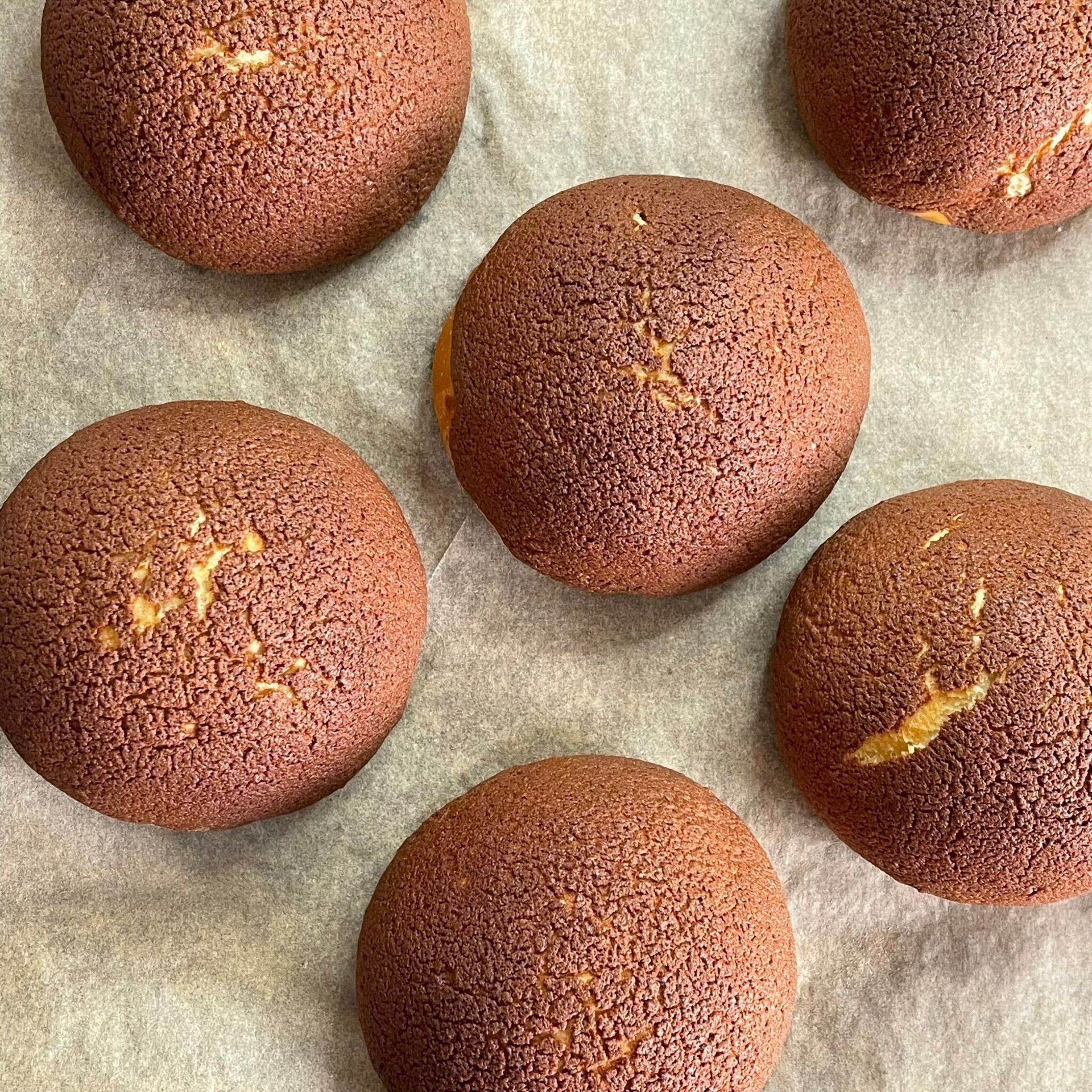 Un gruppo di biscotti al cioccolato appoggiati su un foglio di carta oleata.