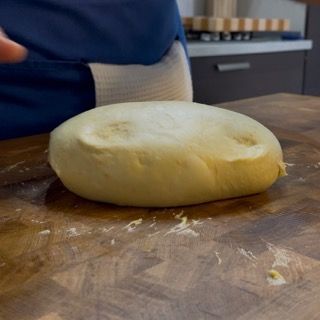 Una persona sta tagliando un pezzo di pasta su un tagliere
