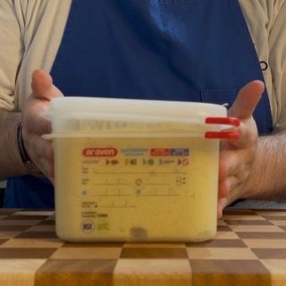 Una persona tiene in mano un contenitore con un coperchio su cui è scritto 