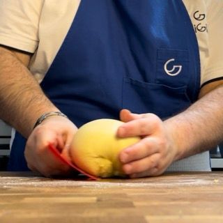 Mani che eseguono le pieghe e pirlano l'impasto a formare una palla.