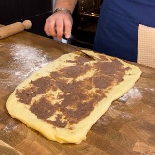 Spatola che stende la crema di burro e cannella sulla sfoglia.
