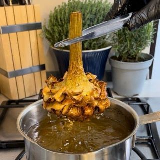 Una persona sta cucinando i carciofi in una pentola di olio