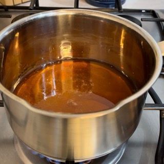 Una pentola piena di liquido marrone sta cuocendo sul fornello.