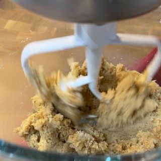 Un mixer sta mescolando un impasto per biscotti in una ciotola di vetro.