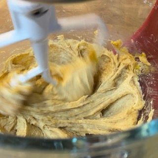 Un mixer sta mescolando una pastella gialla in una ciotola di vetro.