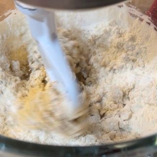 Un mixer mescola farina e burro in una ciotola.