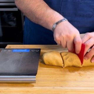 Una persona sta tagliando una pagnotta di pasta su un tagliere