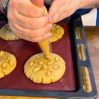 Una persona sta preparando un biscotto con sopra delle noci