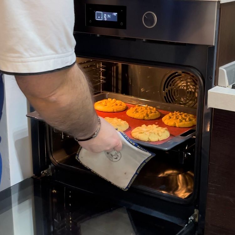 Un uomo sta tirando fuori una teglia di biscotti dal forno