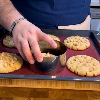 Una persona sta mettendo un biscotto in un anello di metallo su un vassoio di biscotti