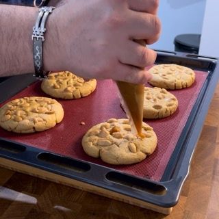 Una persona con un braccialetto al polso sta decorando i biscotti