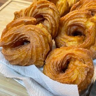 Inserimento della crema pasticcera tramite i fori laterali nella zeppola di san giuseppe fritte.