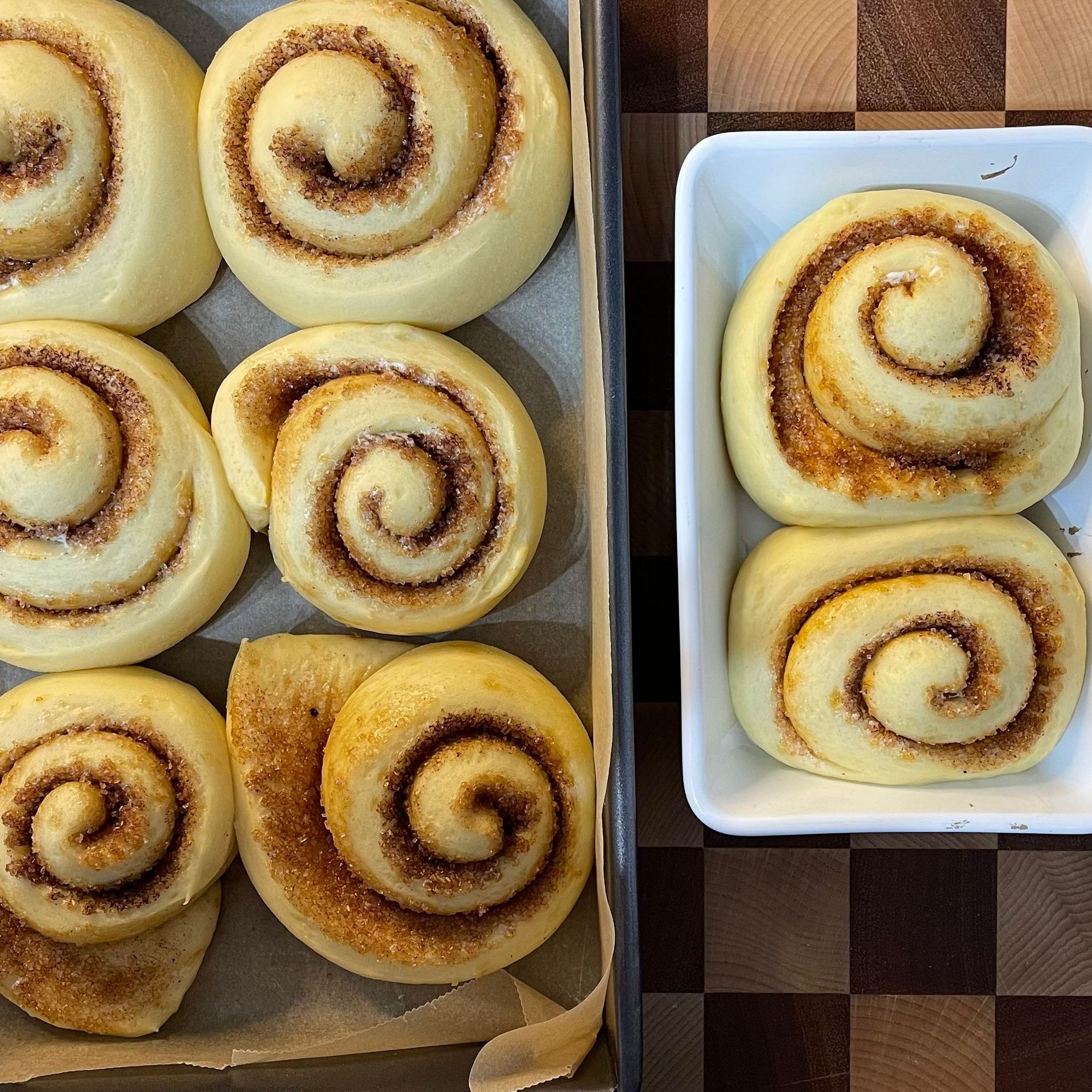 Cinnamon rolls raddoppiati di volume, attaccati l'uno all'altro e pronti per il forno