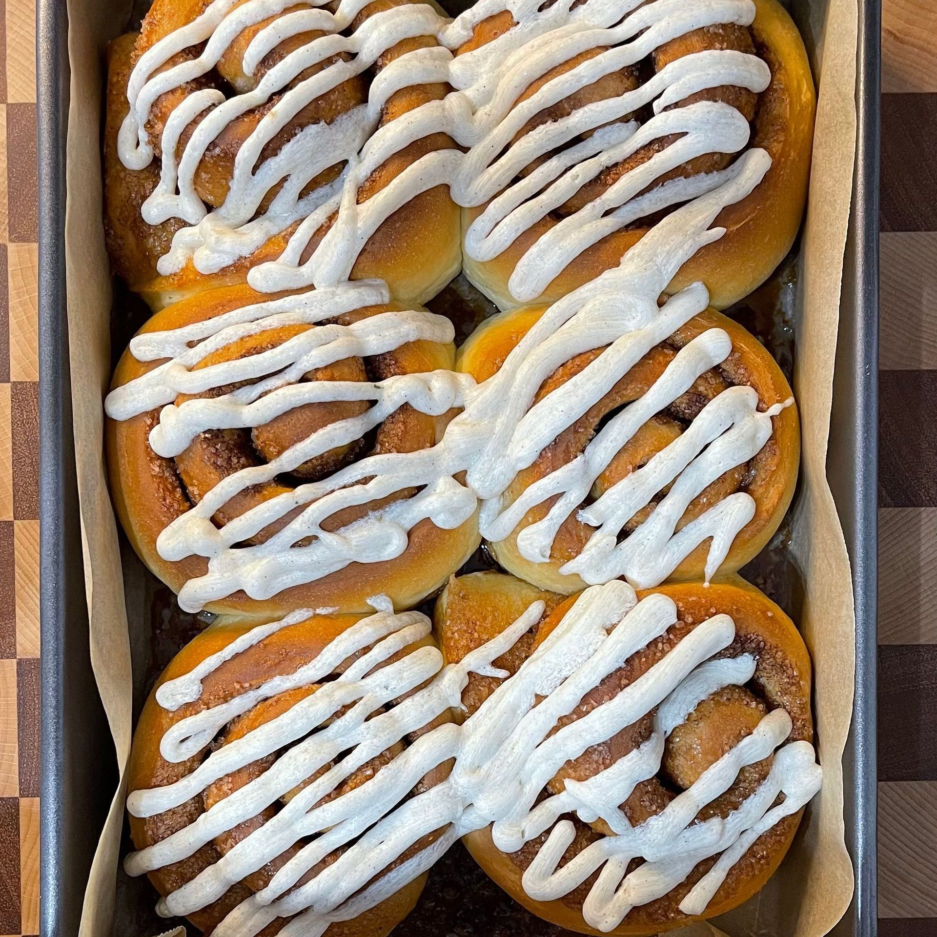 Spatola che distribuisce la glassa bianca sui cinnamon rolls caldi