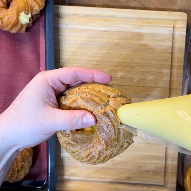 Inserimento generoso della crema all'interno del bignè per una zeppola gourmet.