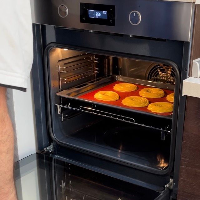 Una persona sta cuocendo delle ciambelle in un forno con lo sportello aperto