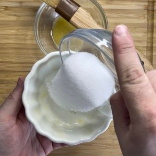 Una persona sta versando lo zucchero in una piccola ciotola