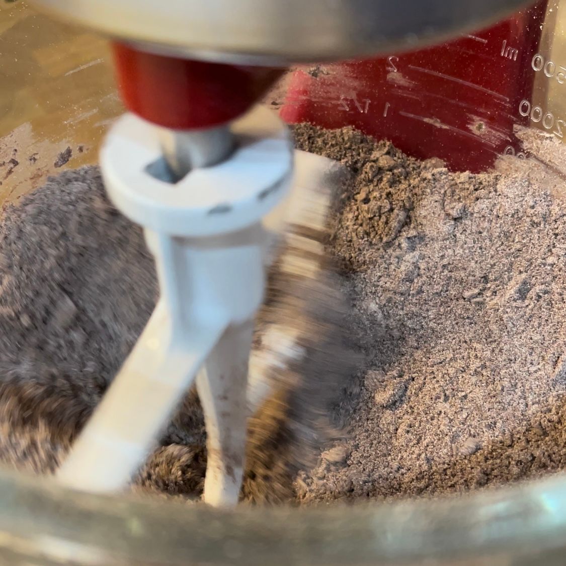 Un mixer sta mescolando una sostanza marrone in una ciotola di vetro.