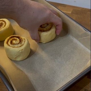 Cinnamon rolls crudi disposti in una teglia, ben distanziati