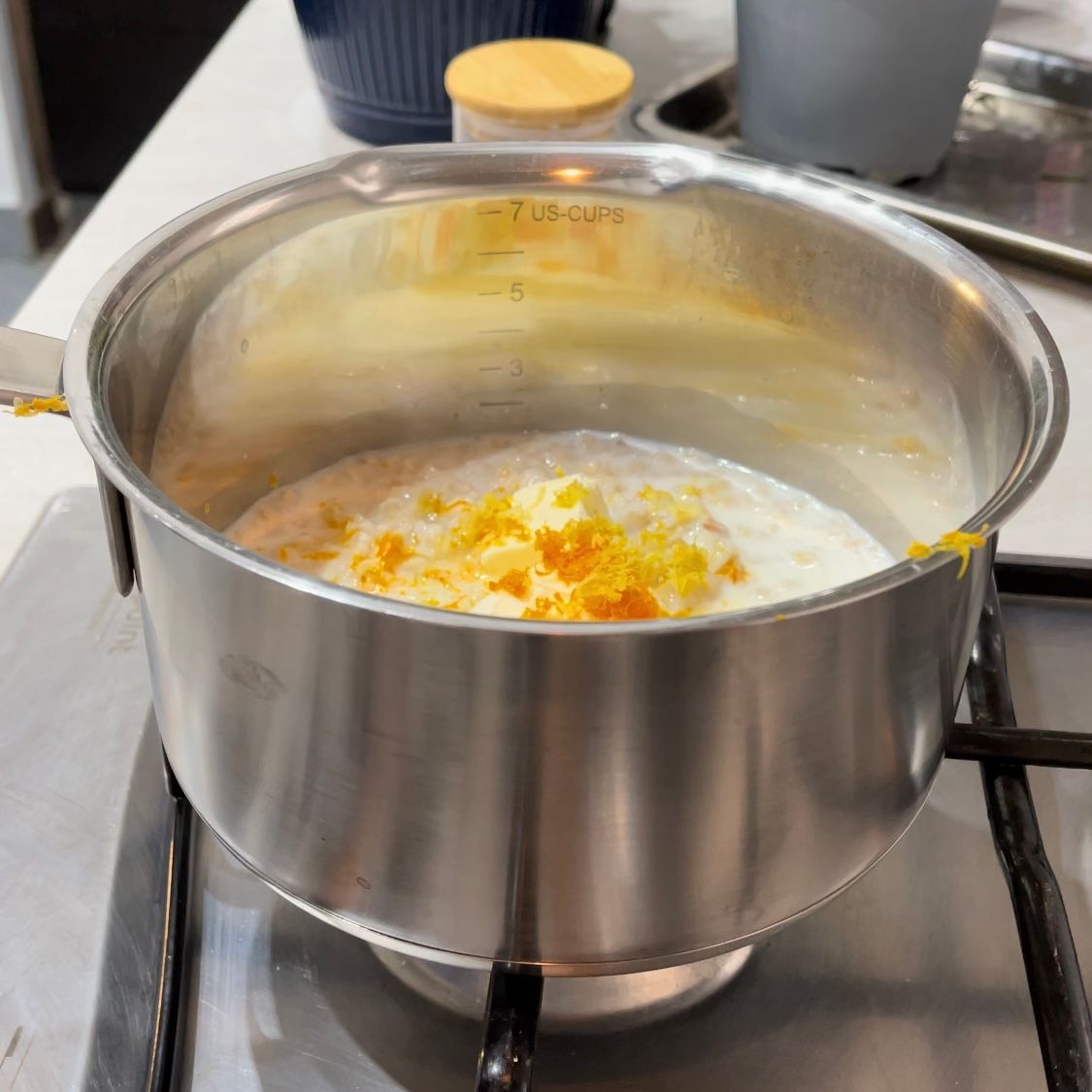 Cottura del grano precotto con latte, burro e scorze di agrumi in pentola.