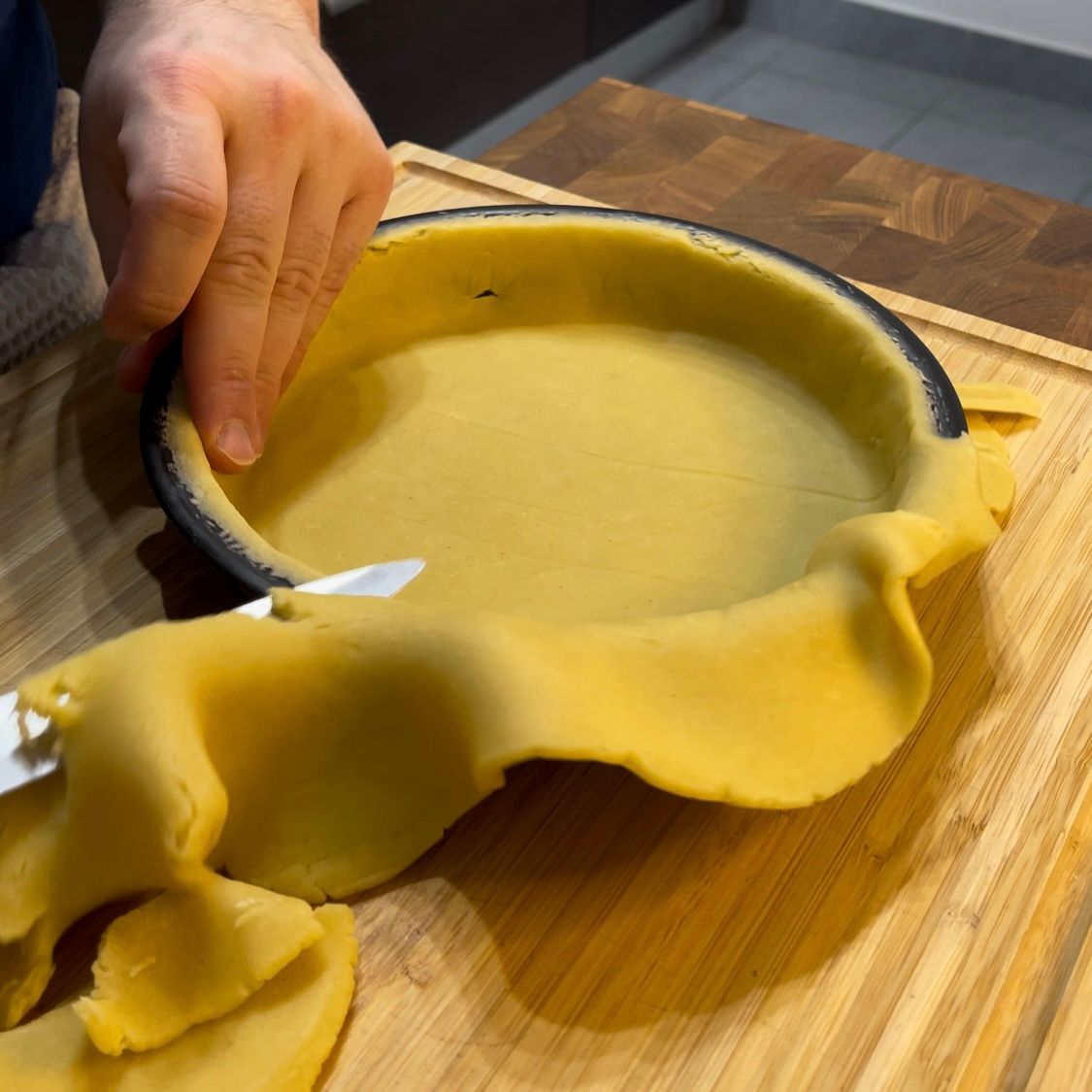 Versamento del ripieno di grano e ricotta nel guscio di frolla crudo.