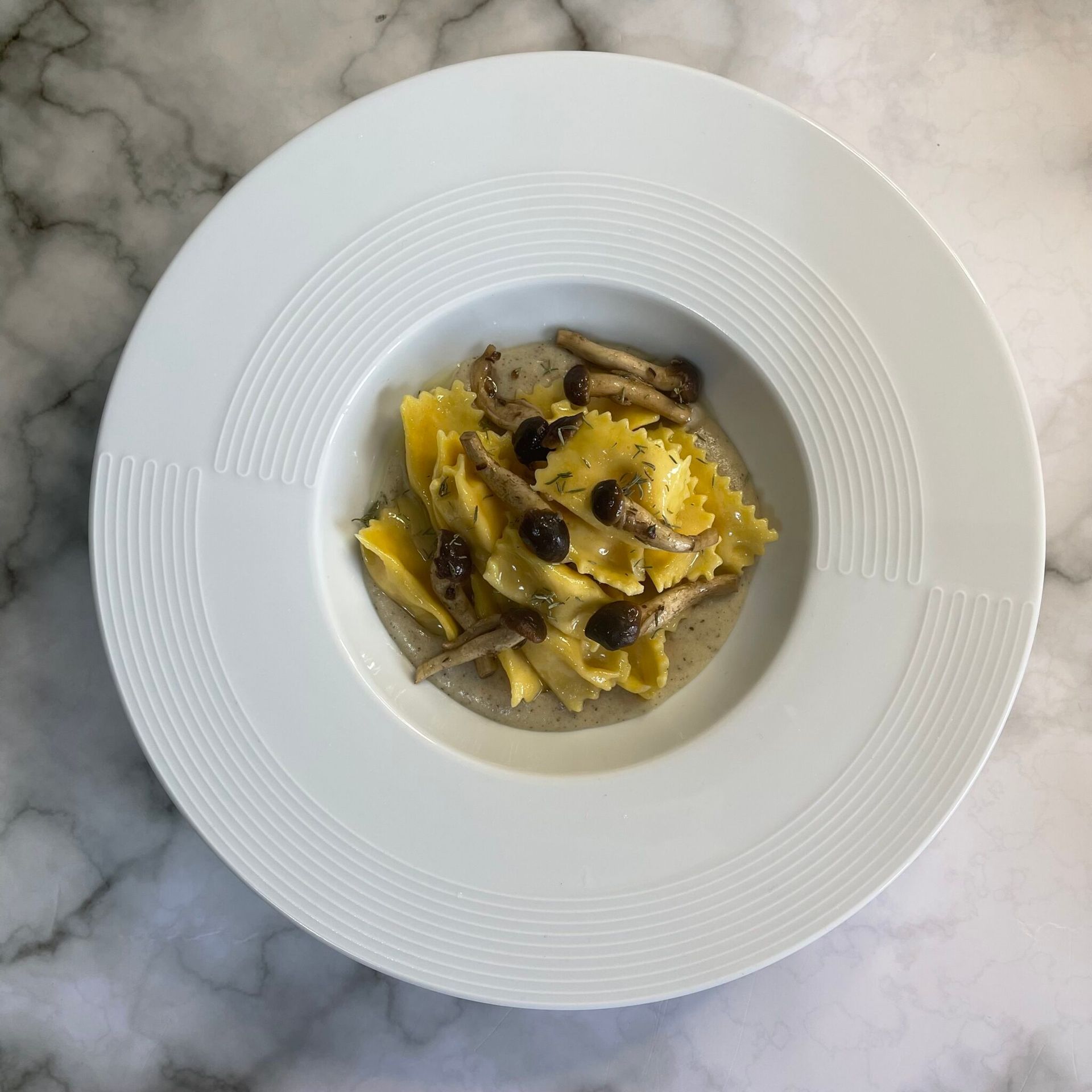 Un piatto bianco con pasta e funghi sopra