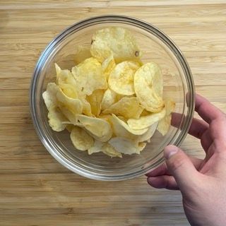 Una persona tiene in mano una ciotola di patatine