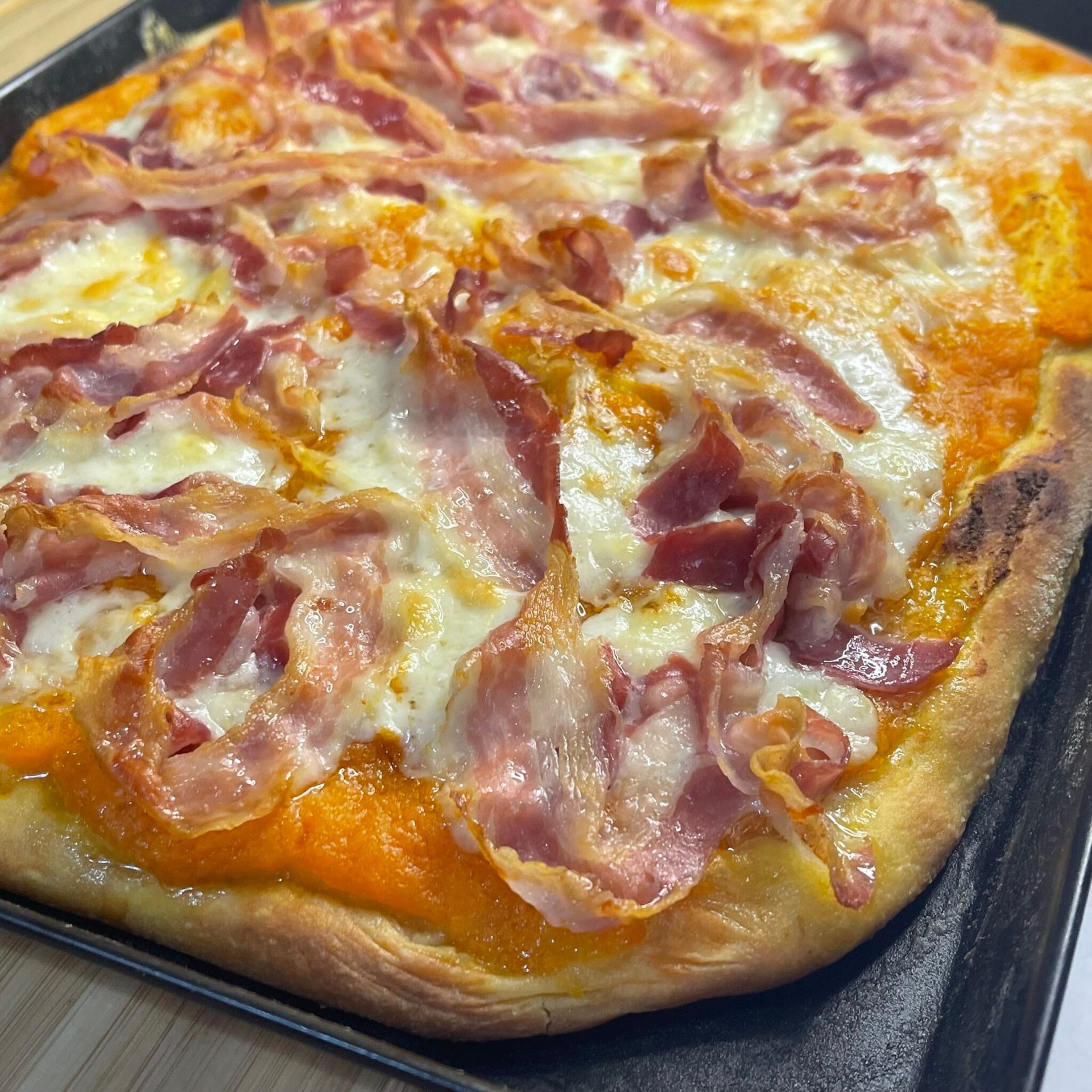 Una pizza con pancetta e formaggio è su una padella