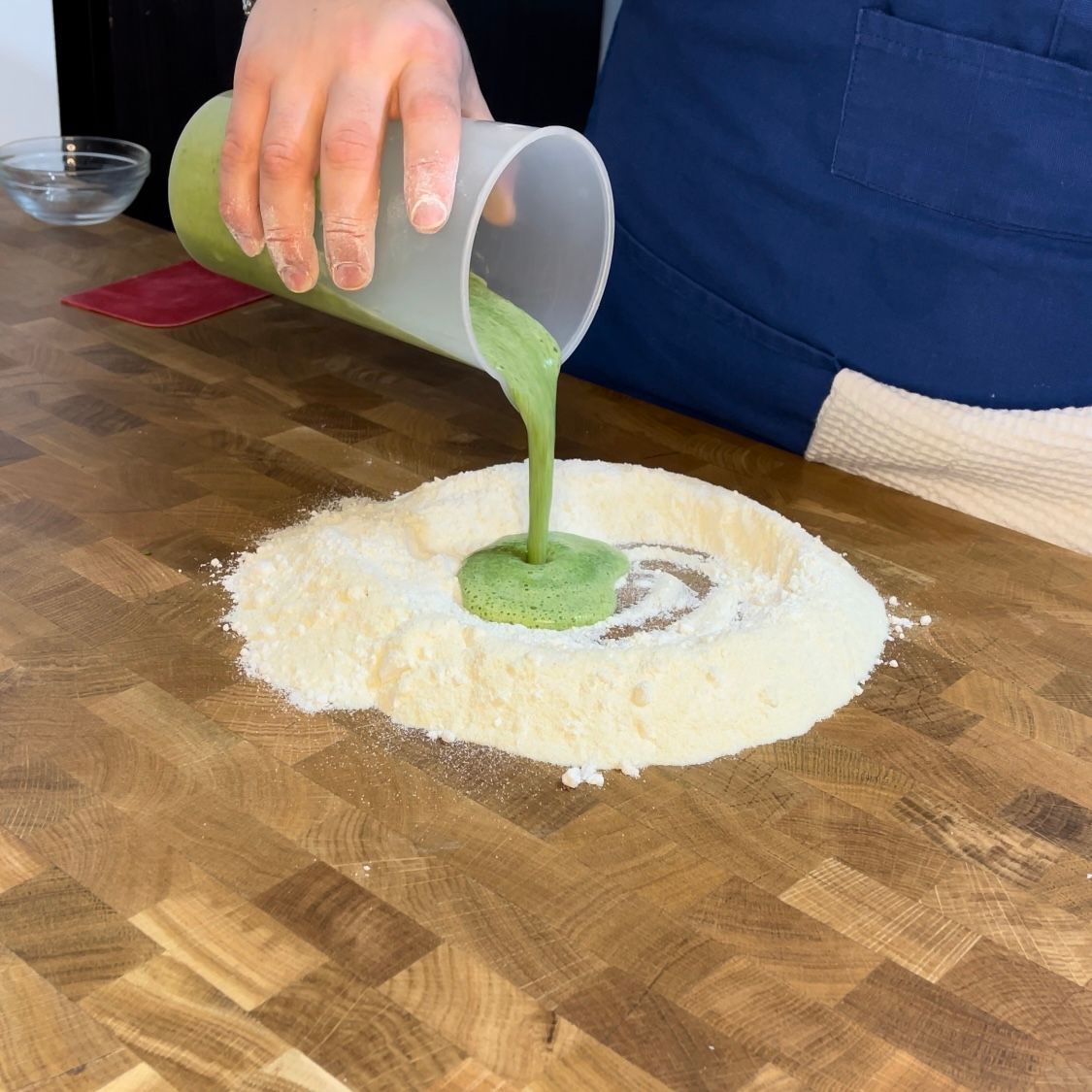 Mix liquido di uova e spinaci versato al centro della farina a fontana.