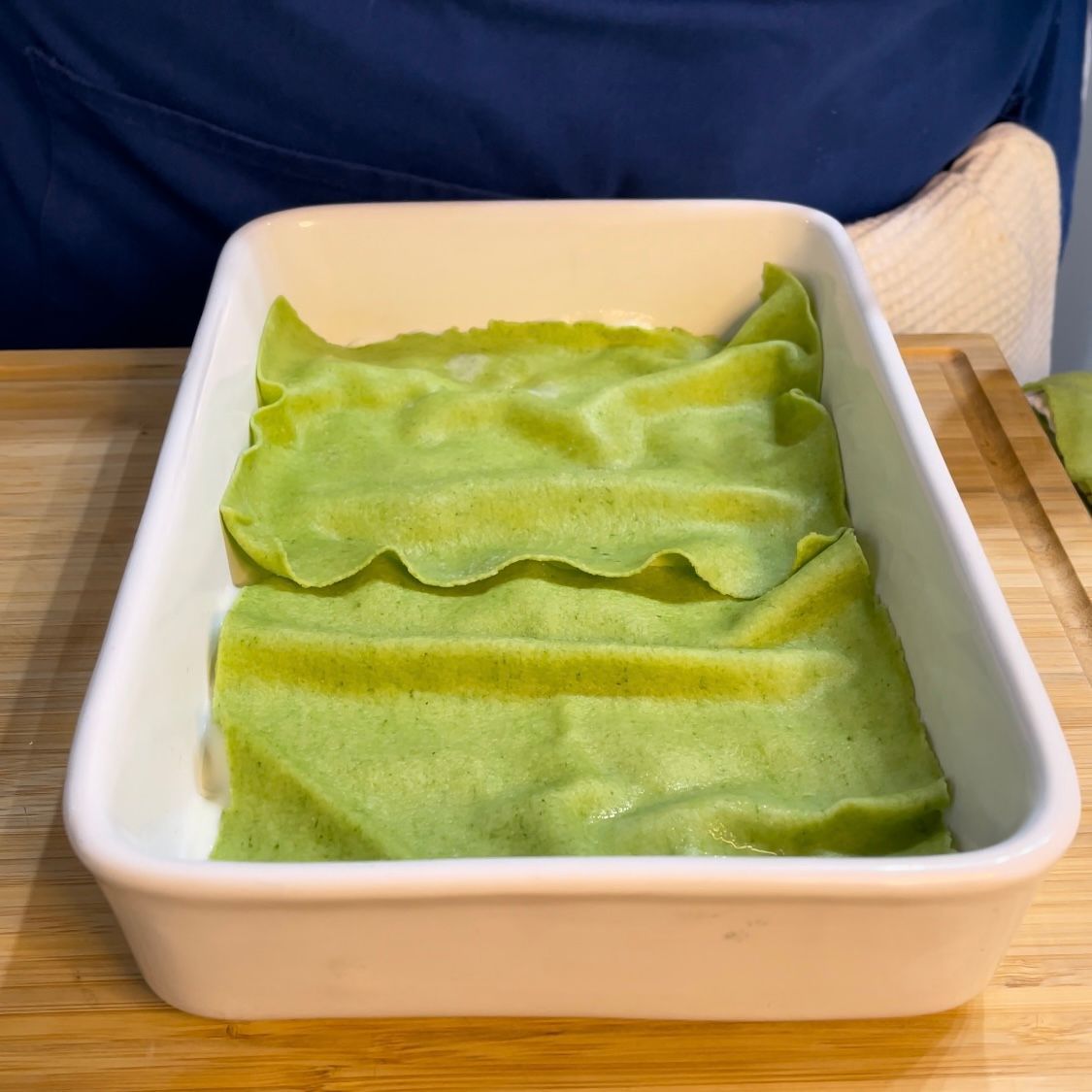 Primo strato di sfoglie di pasta verde adagiato nella teglia.
