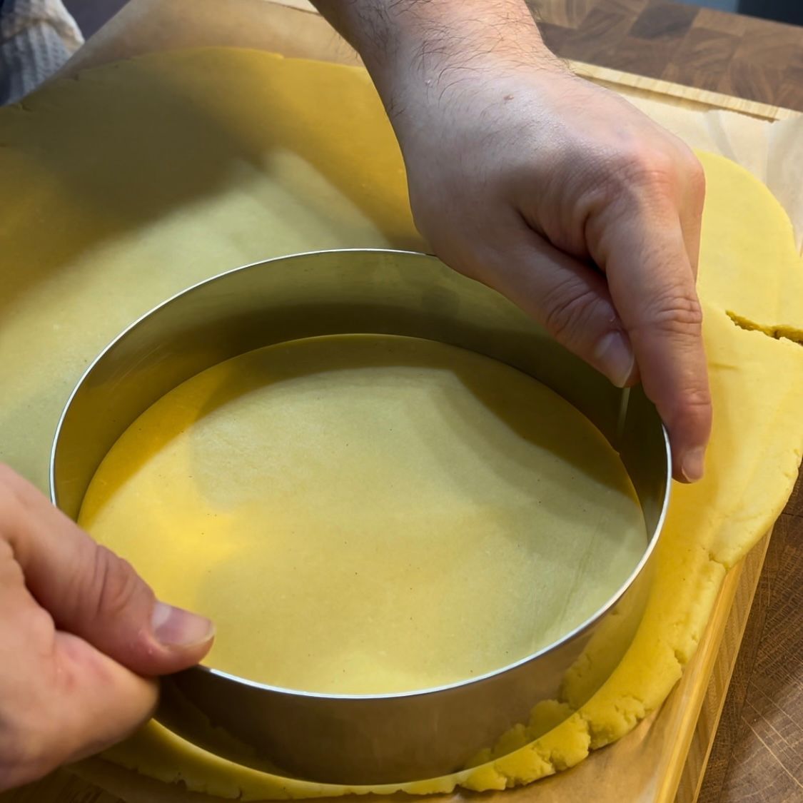 una persona ricava un disco di pasta frolla usando un anello 