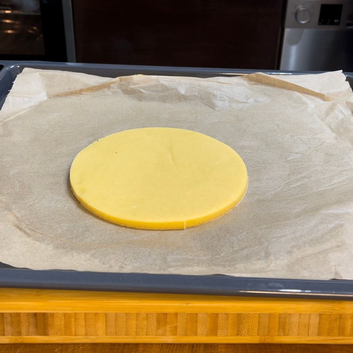 un disco di pasta frolla su una teglia con carta forno 