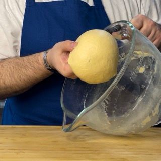 Una persona tiene in mano un limone sopra un misurino di vetro.