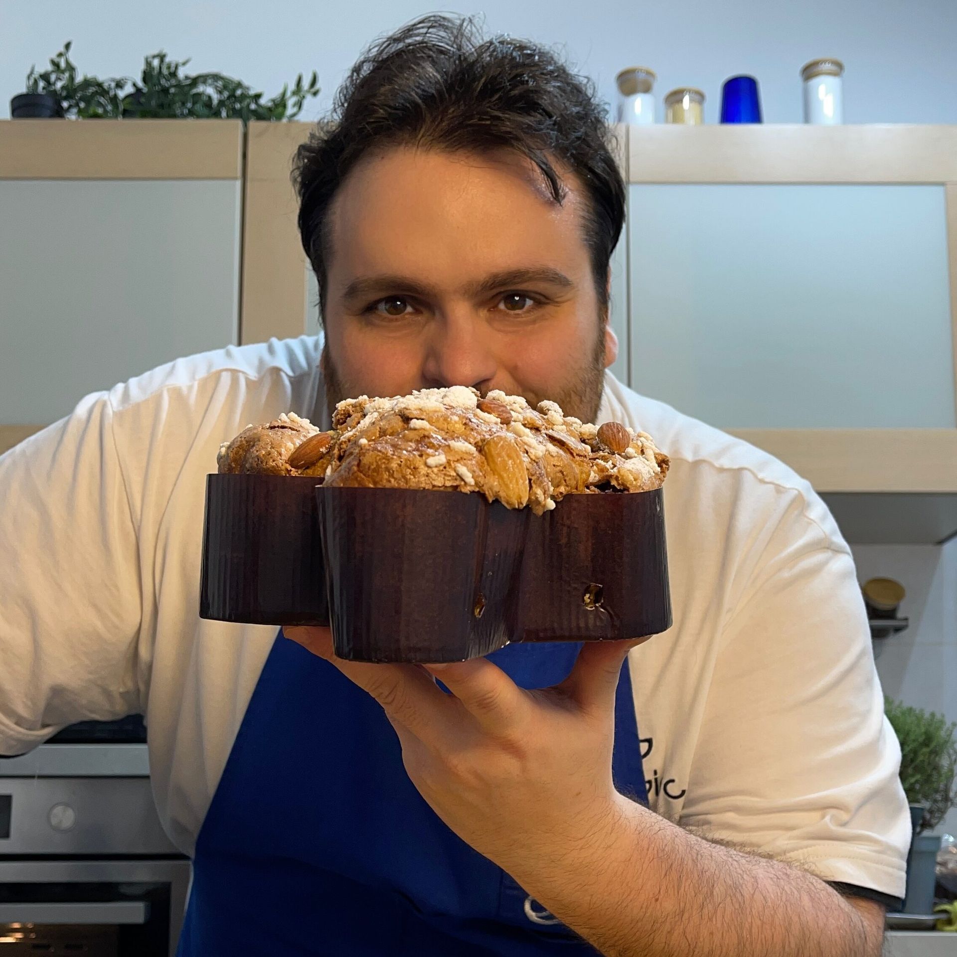 Un uomo con un grembiule blu tiene una torta tra le mani