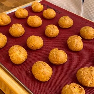 Bignè appena sfornati, perfettamente gonfi e dorati, su una griglia