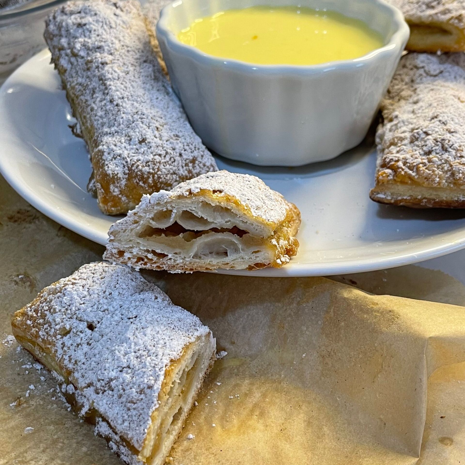 Un piatto bianco con sopra dei pasticcini e una ciotola di salsa gialla
