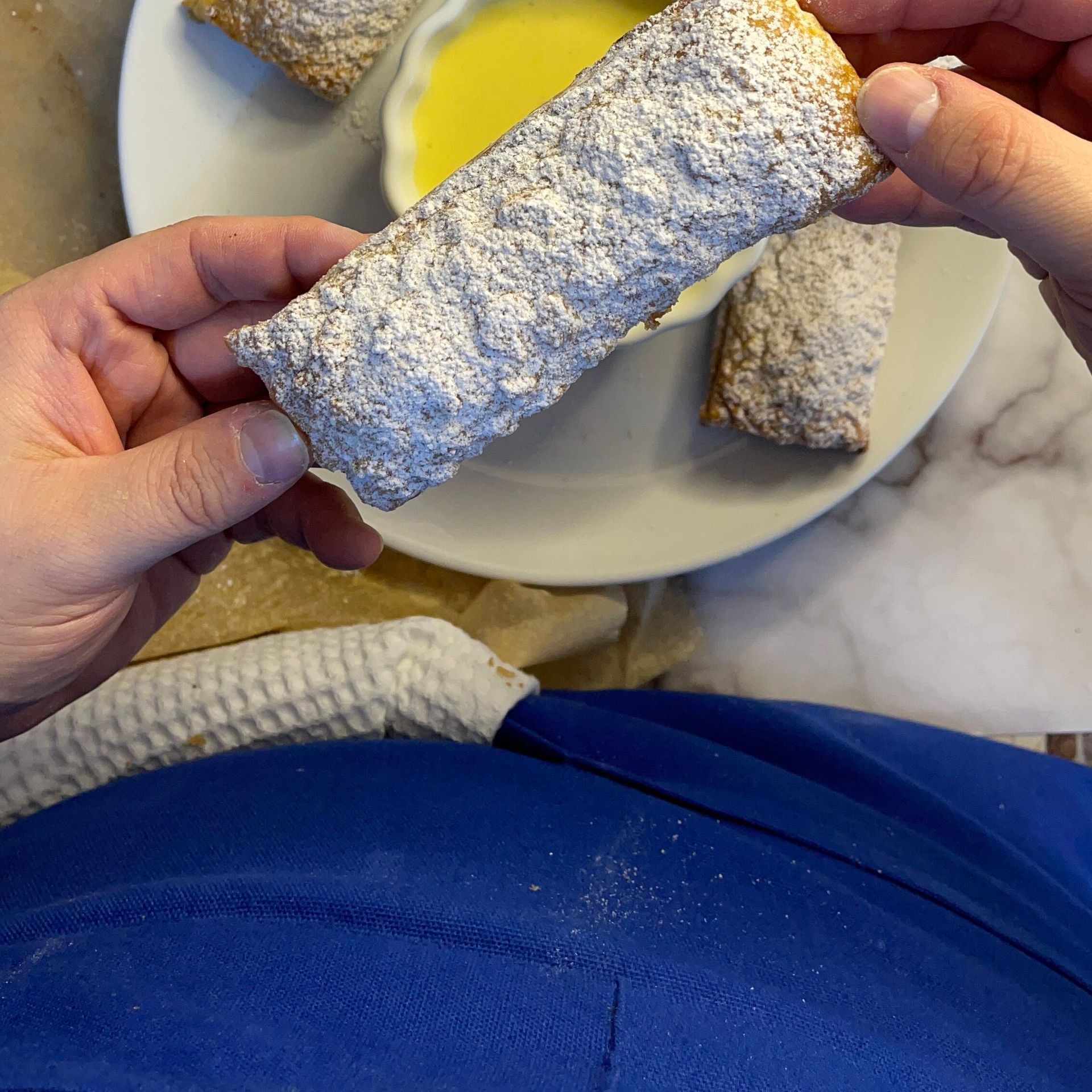 Una persona tiene in mano un pezzo di torta con sopra dello zucchero a velo