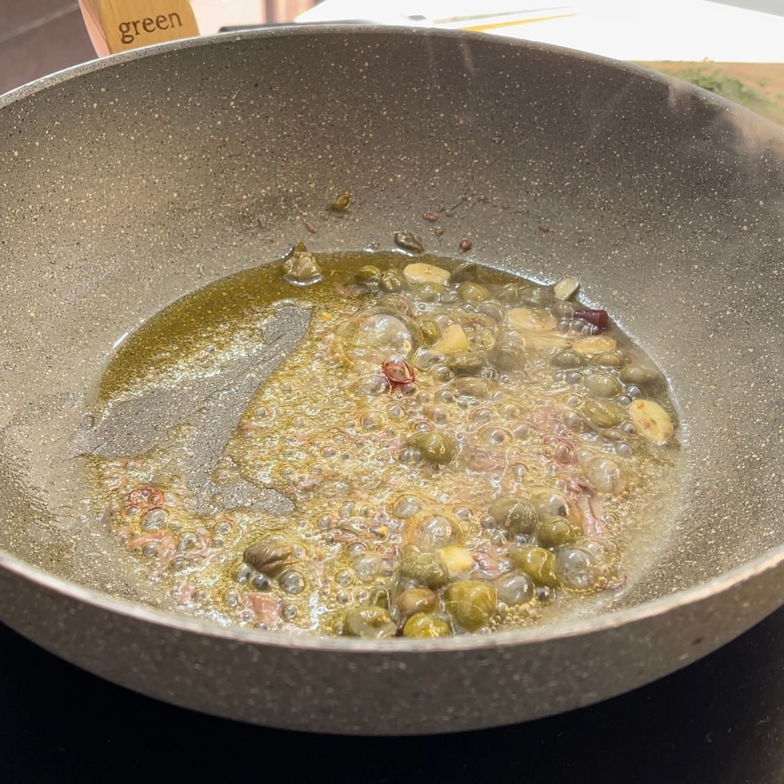 Una padella piena di verdure e olio con la parola verde sullo sfondo