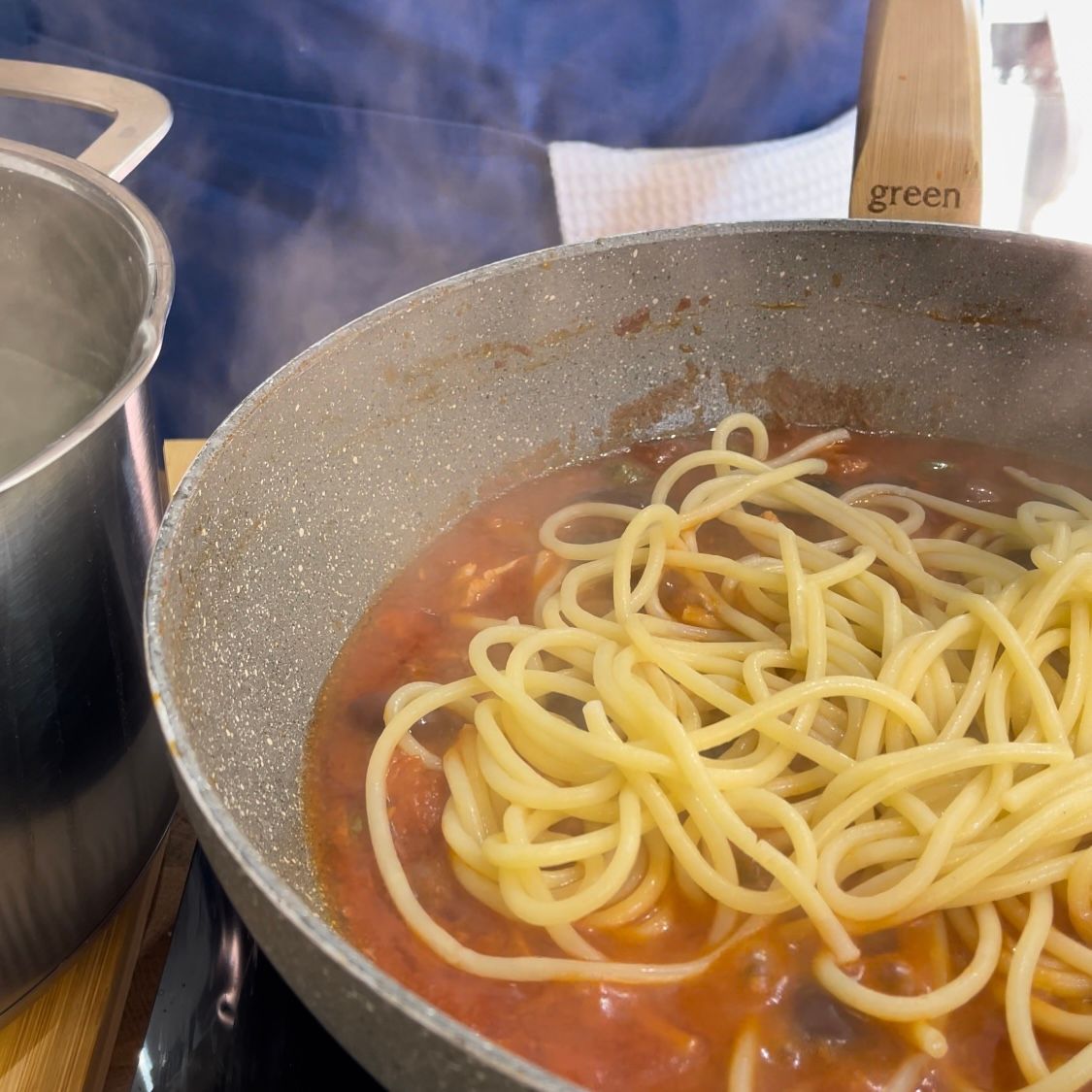 Una padella piena di spaghetti e salsa con un manico verde