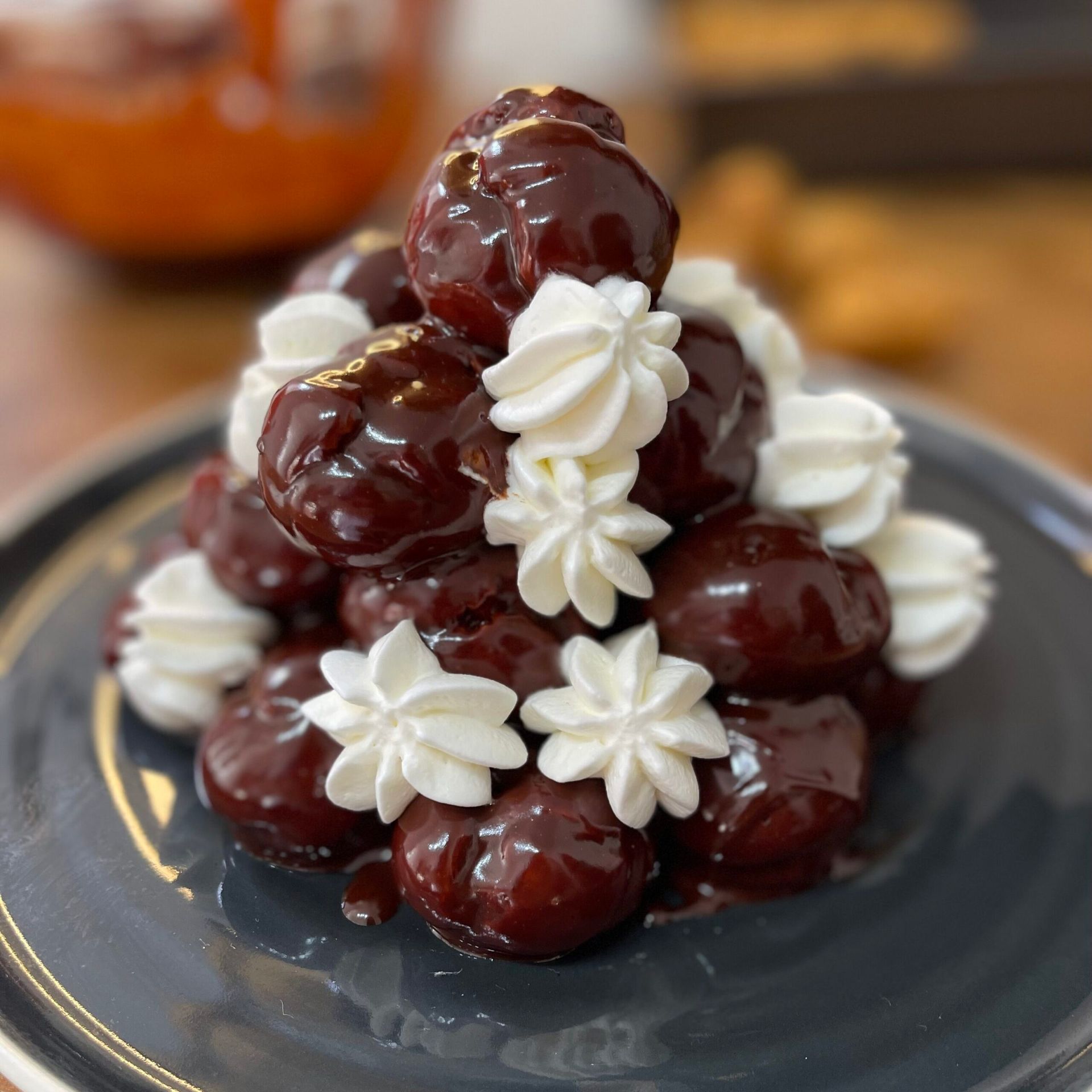 Una piramide di ciliegie ricoperte di cioccolato e panna montata su un piatto