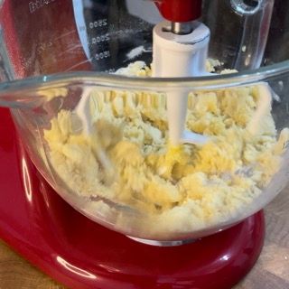 Un mixer rosso con una ciotola di vetro piena di purè di patate