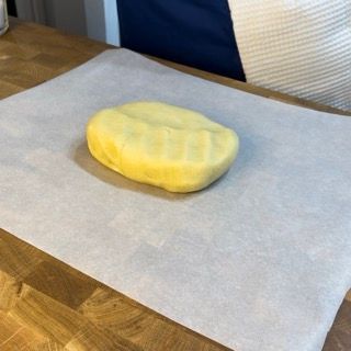 Un pezzo di pasta gialla è appoggiato su un pezzo di carta oleata