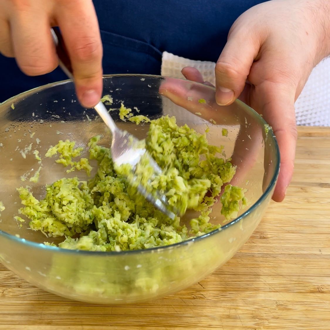 Una persona sta mescolando il riso verde in una ciotola con una forchetta